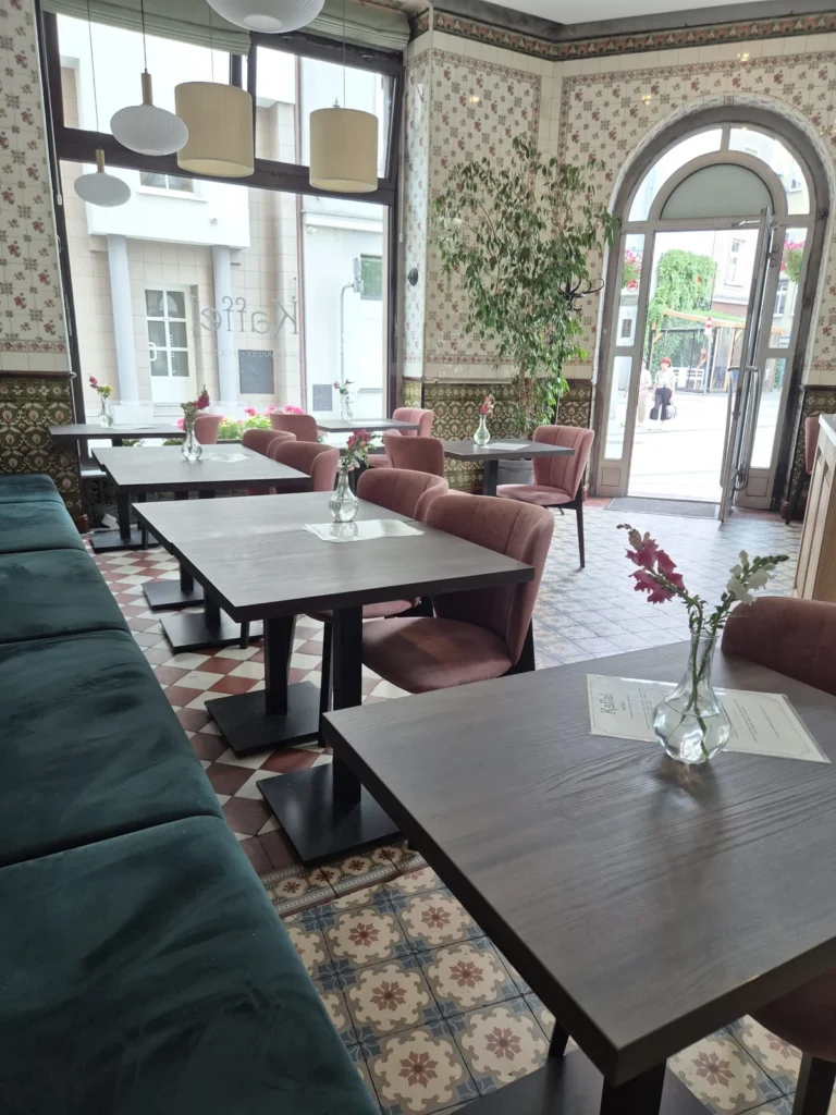 Zestawienie zielonej loży Paris i różowych krzeseł tapicerowanych w sali piekarnio-kawiarni Kaffel w Gliwicach