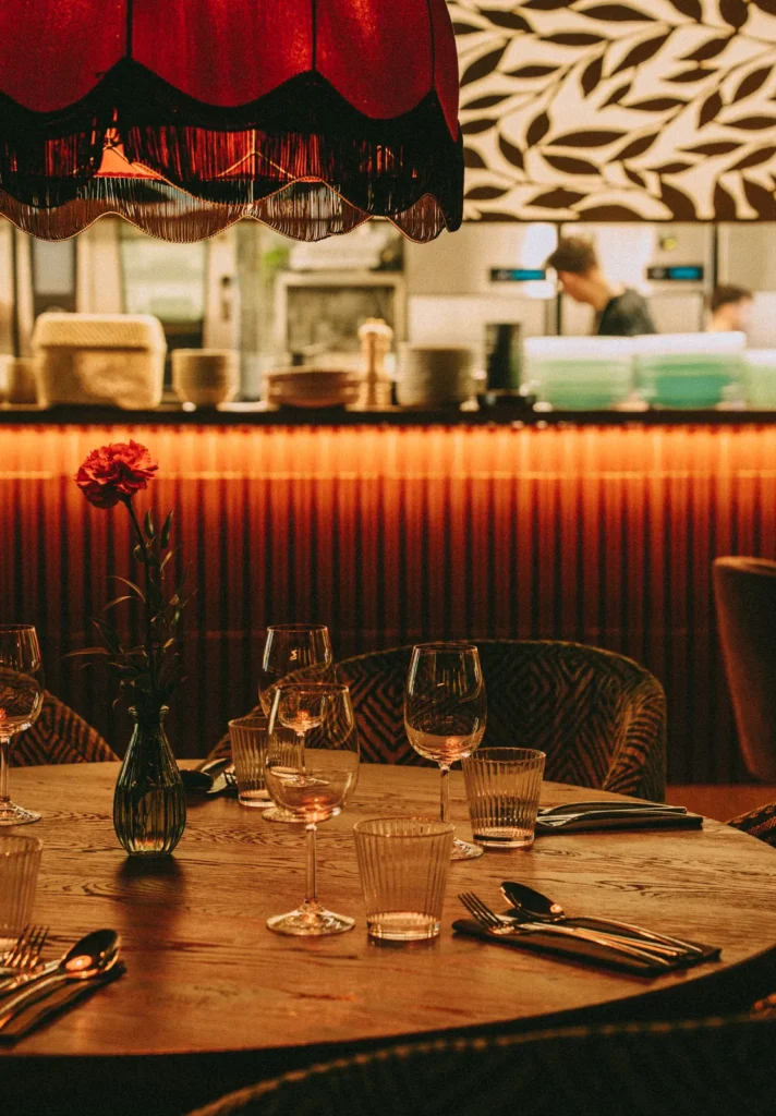 Krzesła tapicerowane przy okrągłym stole naprzeciw otwartej kuchni w restauracji Restbotanica w Katowicach