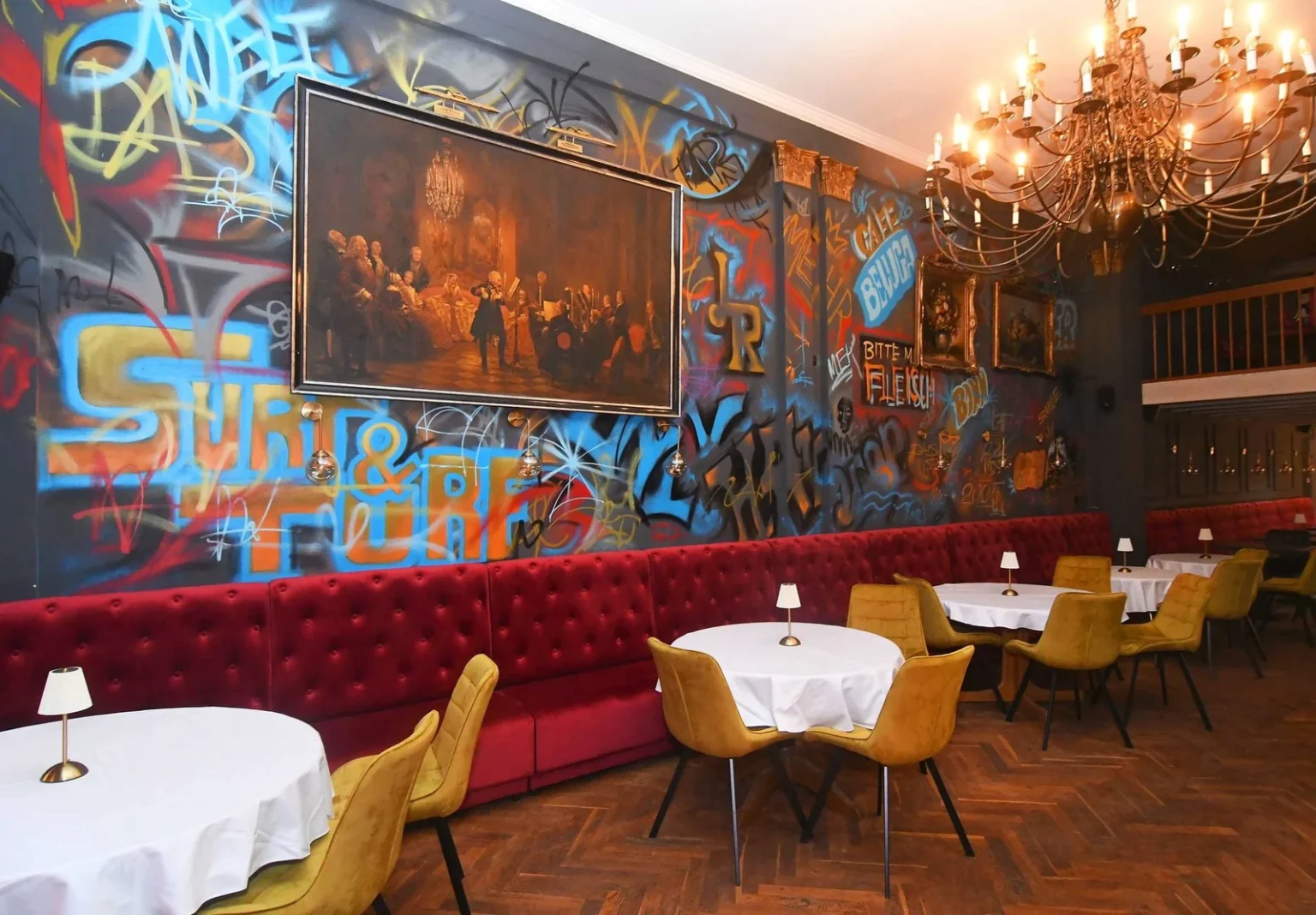 Czerwona loża chesterfield na wymiar wzdłuż ściany z muralem w Cafe Beluga w Bonn