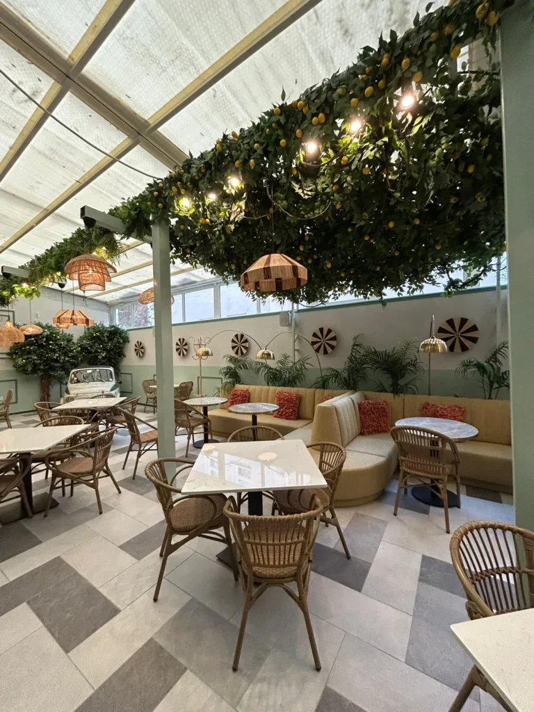 Loża Paris na wymiar wzdłuż ściany przeszklonej sali restauracji w Budapeszcie, pod zadaszeniem z cytrynowej zieleni