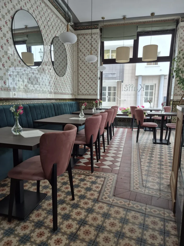 Ciągła loża Paris w butelkowej zieleni wzdłuż ściany z okrągłymi lustrami w kawiarni Kaffel w Gliwicach