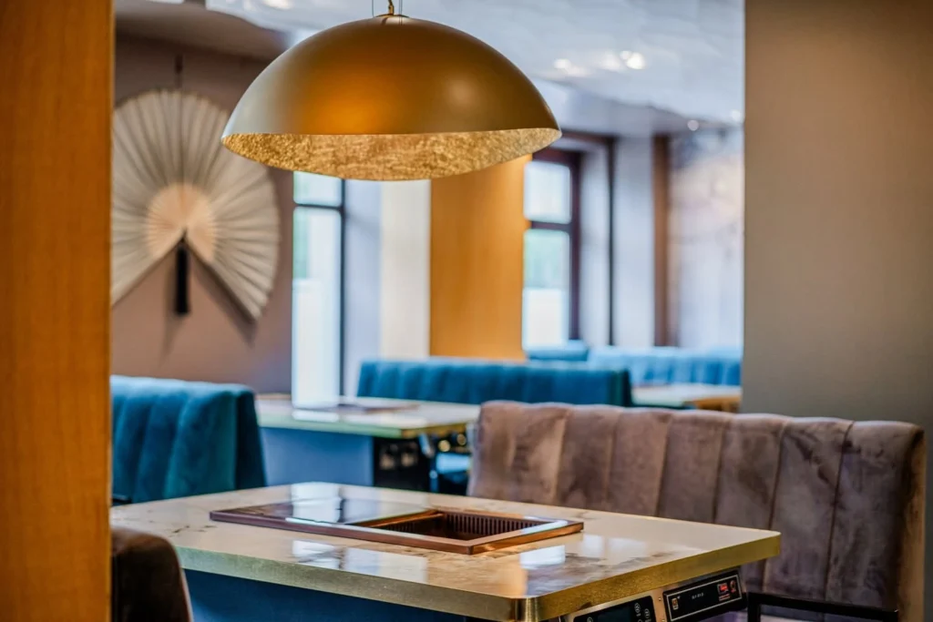 Podkowa półokrągłej loży wokół okrągłego stołu z płytą grillową w restauracji w Poznaniu
