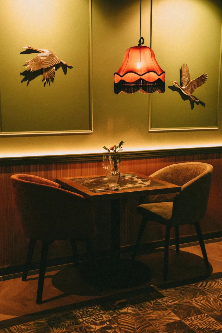 dwa krzesła przy stoliku, ciepłe światło, zielona ściana | Dwa krzesła 121 przy dwuosobowym stoliku w restauracji